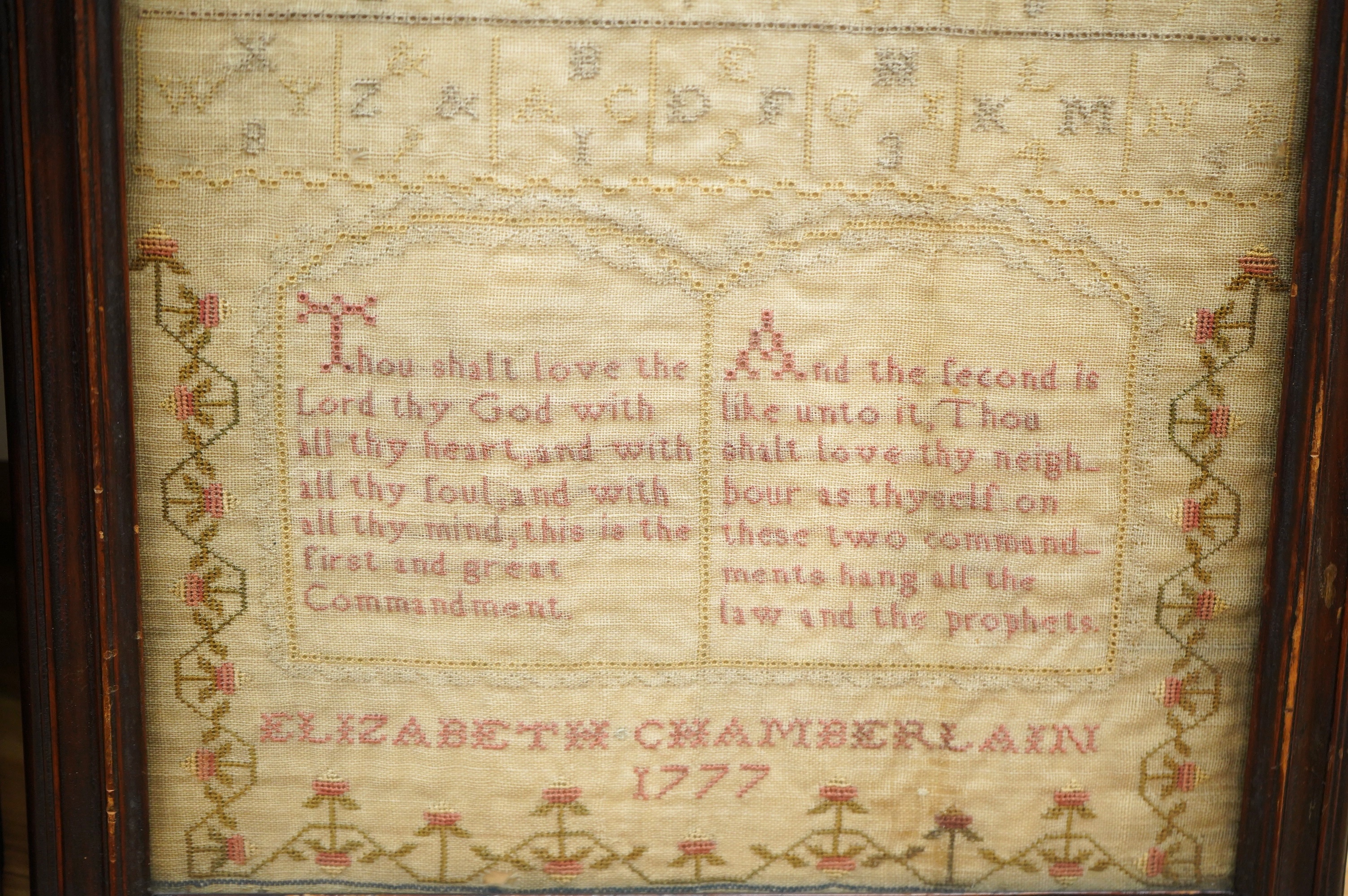 Two samplers; one late 18th century, the other early 20th century, the 18th century sampler by Elizabeth Chamberlain dated 1777, worked with an alphabet and framed verse bordered with vineous flowers, the later sampler b